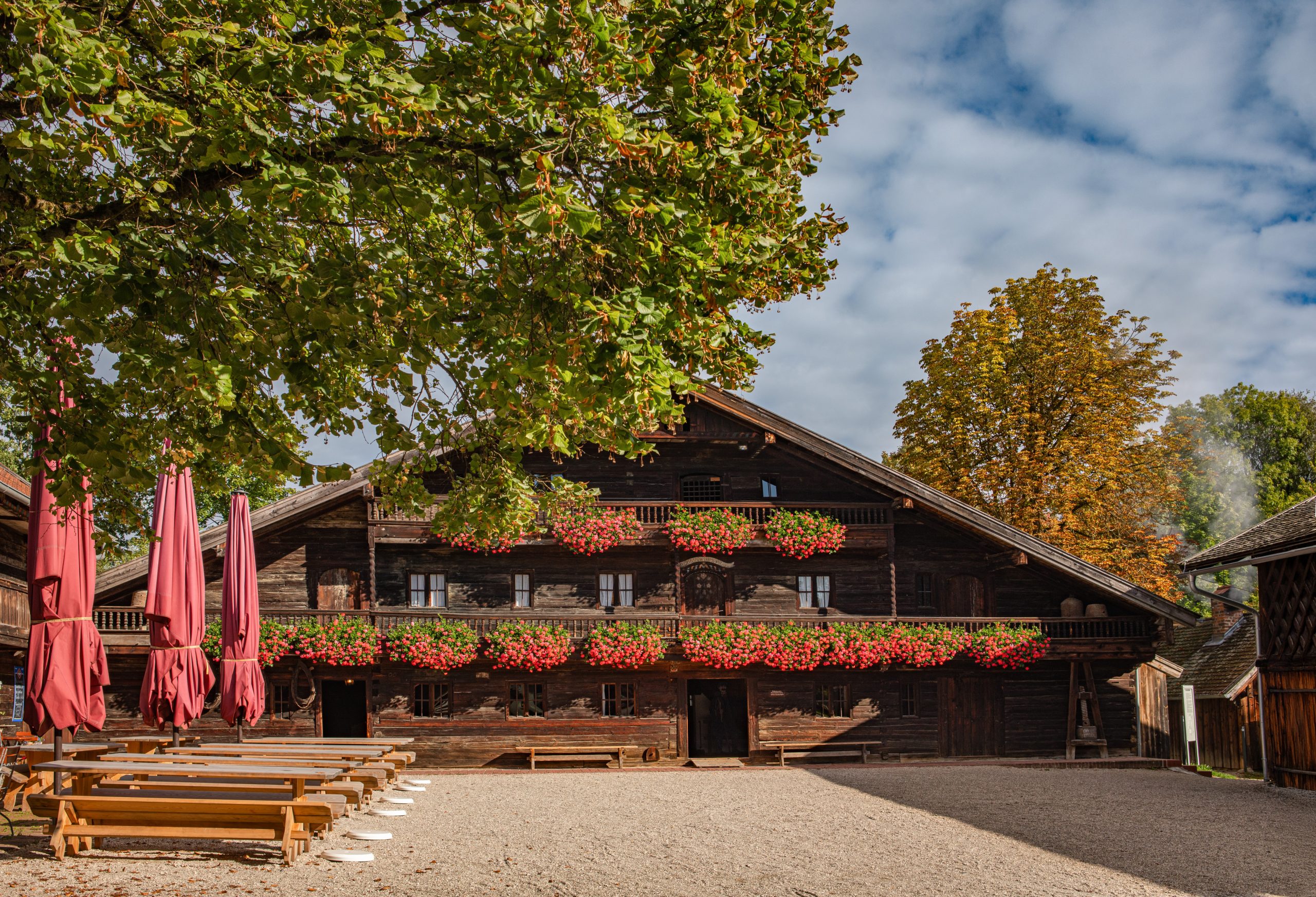Historisches Holzhaus, im Vordergrund Kastanie und Biergarten