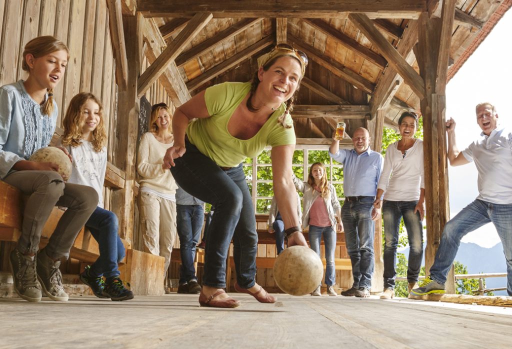 Eine Gruppe kegelt auf einer hölzernen Kegelbahn.